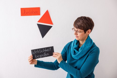 Lisi Weihs hält ein Schild mit "Wirklichkeit begreifen" hoch